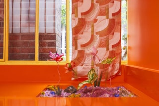 orange surface with rectangular cutout in which multicolored paper flowers are planted