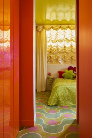 Pinkandgreen carpeting with squiggle line and polka dot pattern through an orange doorway a bedroom with bright green...
