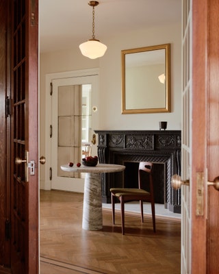 The foyers original fireplace greets guests with a dramatic flair. Combined with a CB2 table a reupholstered vintage...